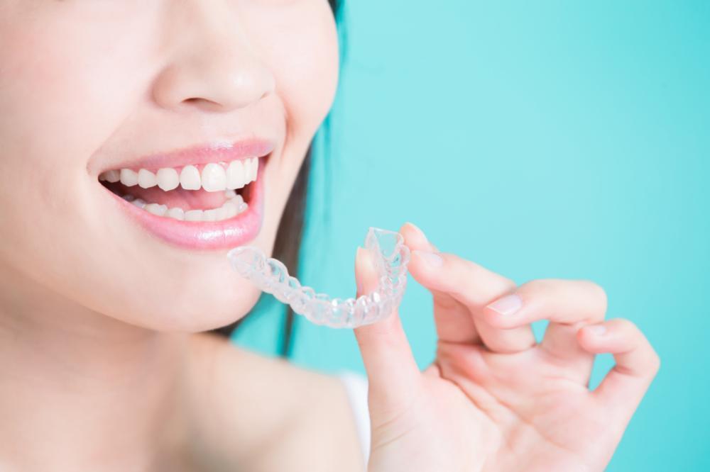 a woman holds her invisalign aligner | invisalign pascoe vale