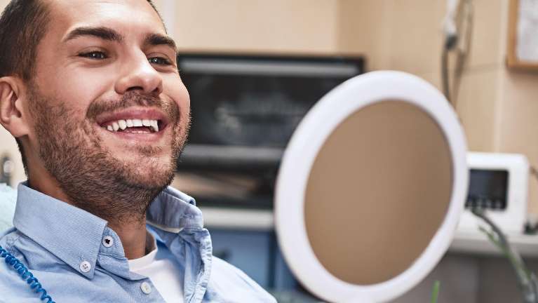 Man in dental chair looking at teeth in mirror, pascoe vale