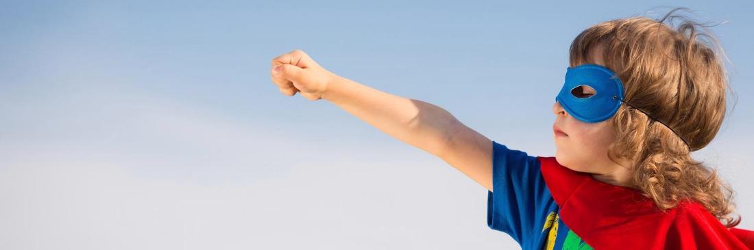 a child with a super hero outfit on sticks his fist to the wind, pretending to fly